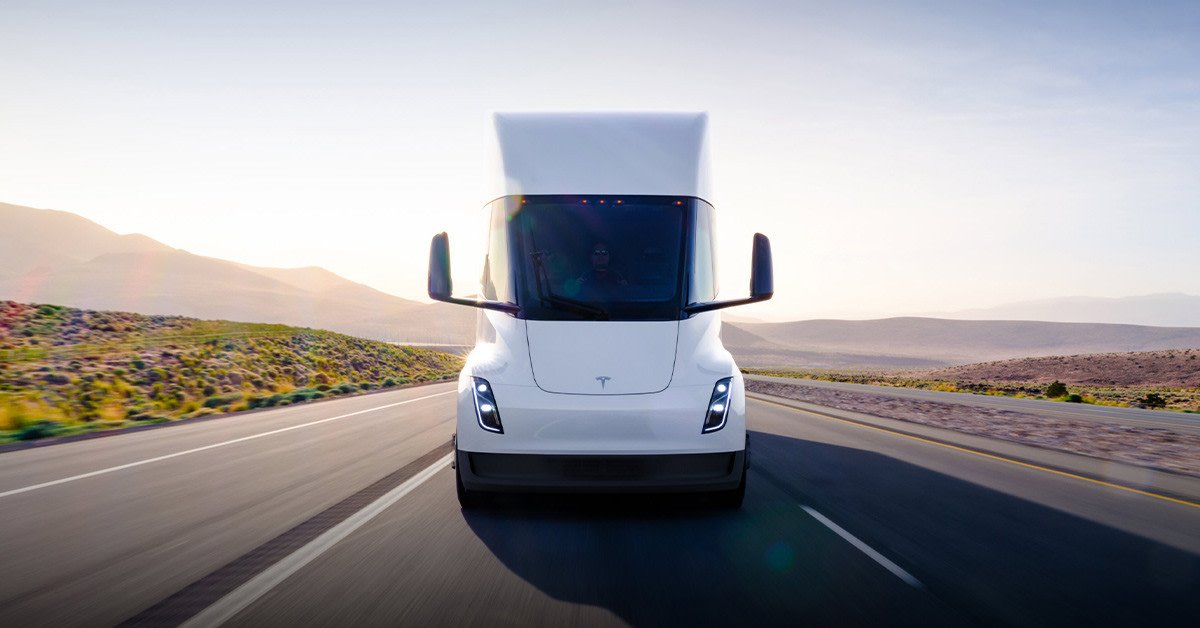 White Tesla Semi electric truck driving on a desert highway at sunset