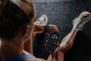 Person wearing the QALO SL-1 smart band checking the Q Score app on a phone