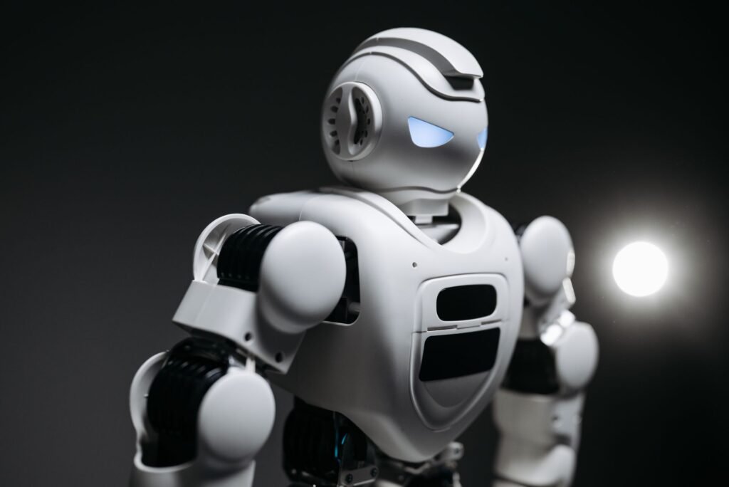Close-up studio photograph of a white humanoid robot with glowing blue eyes against a black background