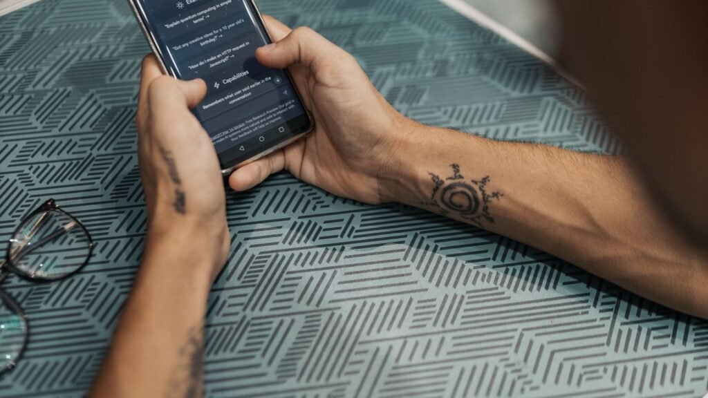 A person using ChatGPT on a smartphone held in both hands at a table