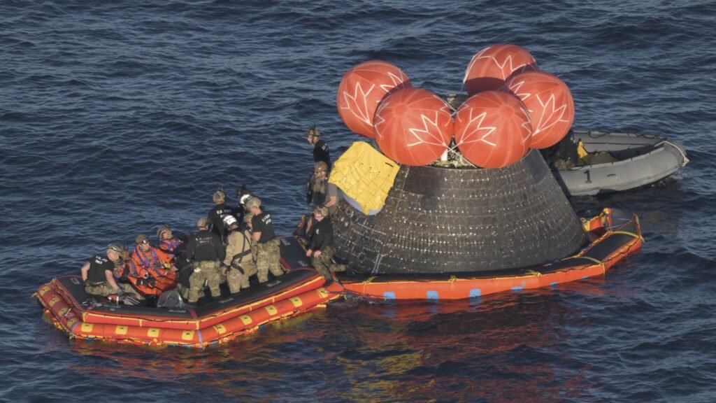 Charred Artemis II Orion capsule floating in the Pacific as the crew is extracted onto rafts after splashdown
