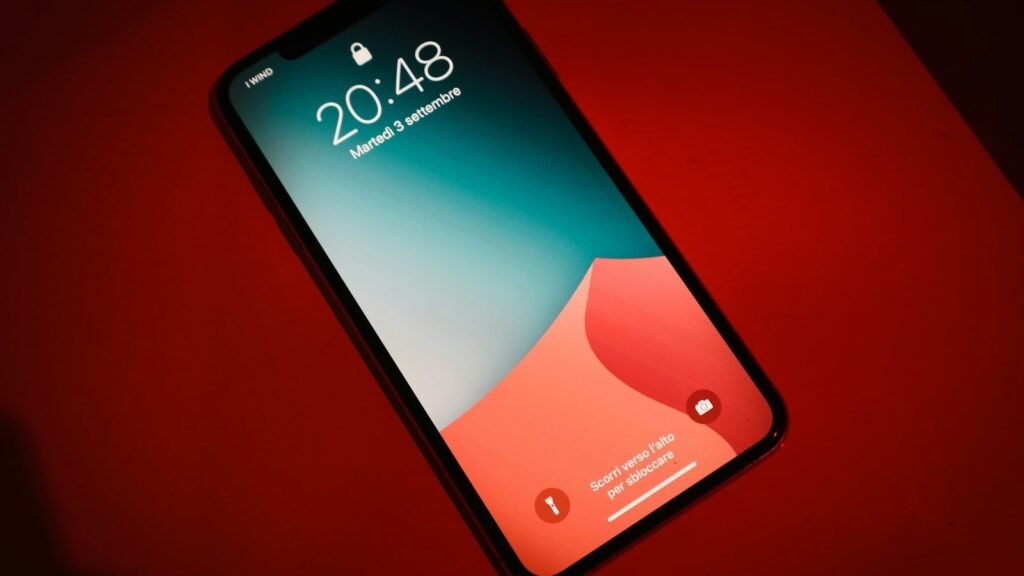 A smartphone glowing red in darkness, its lit screen evoking an urgent phone alert.