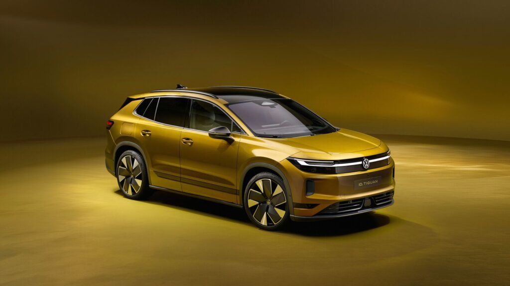 Volkswagen ID. Tiguan electric SUV in gold, front three-quarter view under dramatic studio lighting