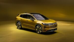 Volkswagen ID. Tiguan electric SUV in gold, front three-quarter view under dramatic studio lighting