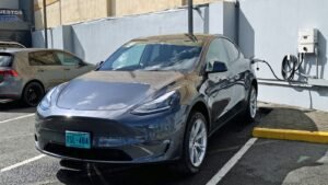 A dark gray Tesla Model Y plugged into a home wall charger with the charge cable connected