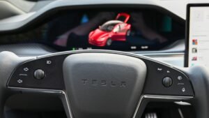 Close-up of a Tesla yoke steering wheel and instrument cluster showing the driver-assistance visualization