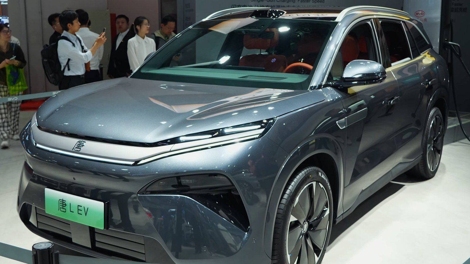 Silver BYD Tang L electric SUV — the model Europe gets as the Atto 8 — plugged into a fast charger at an auto show