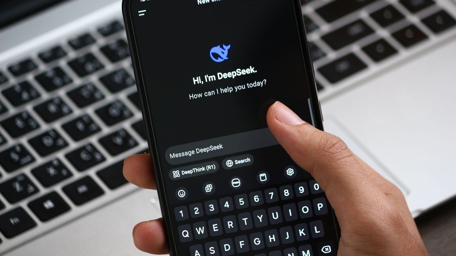 Hand holding a phone showing the DeepSeek chat app with its blue whale logo