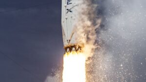 SpaceX Falcon 9 rocket climbing with bright engine plume against a dark sky
