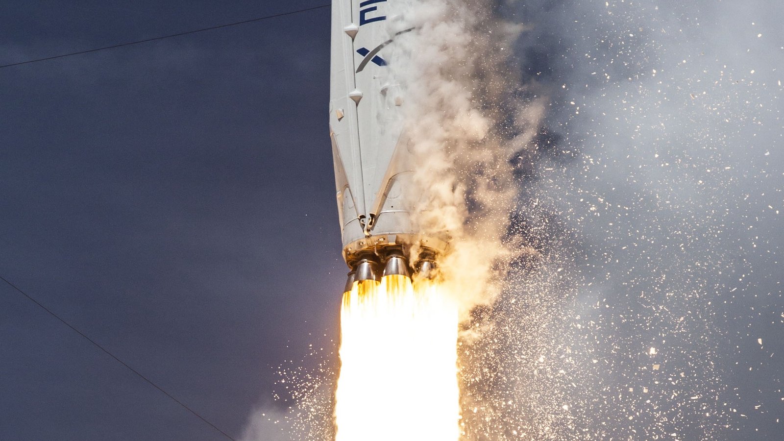SpaceX Falcon 9 rocket climbing with bright engine plume against a dark sky