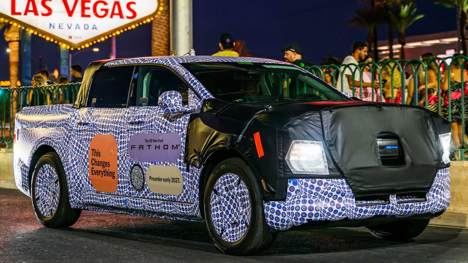 Camouflaged Ford Fathom electric pickup prototype on the road in Las Vegas at night with headlights on