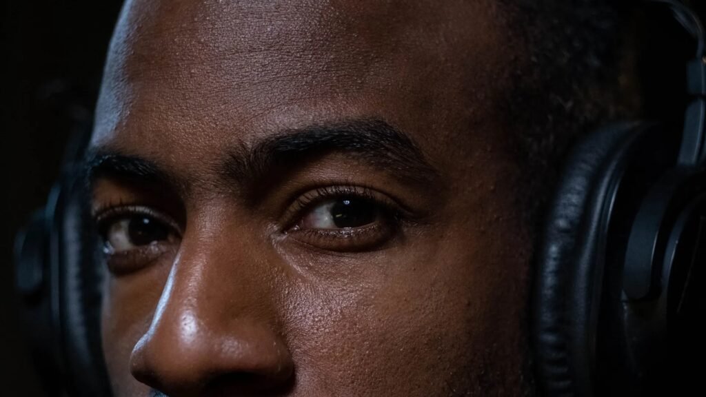 Close-up portrait of a person wearing black over-ear headphones in dramatic low light