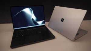 Two Microsoft Surface Laptop Ultra laptops side by side, one open showing the Windows 11 desktop and one showing the Windows logo on the lid