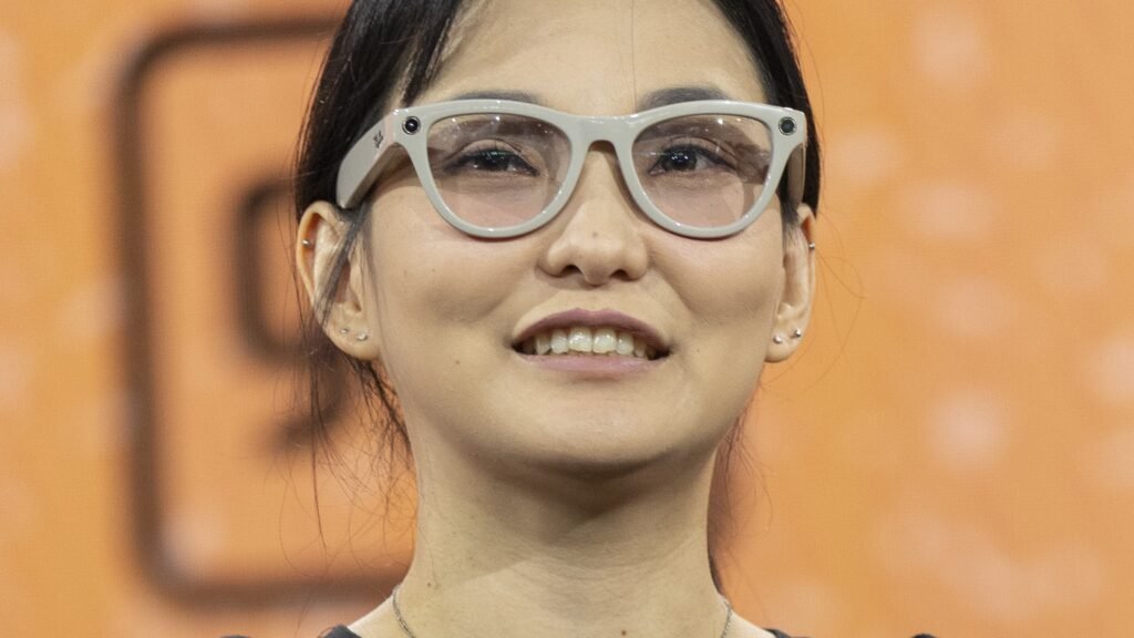 A woman wearing Ray-Ban Meta smart glasses with the camera visible on the frame