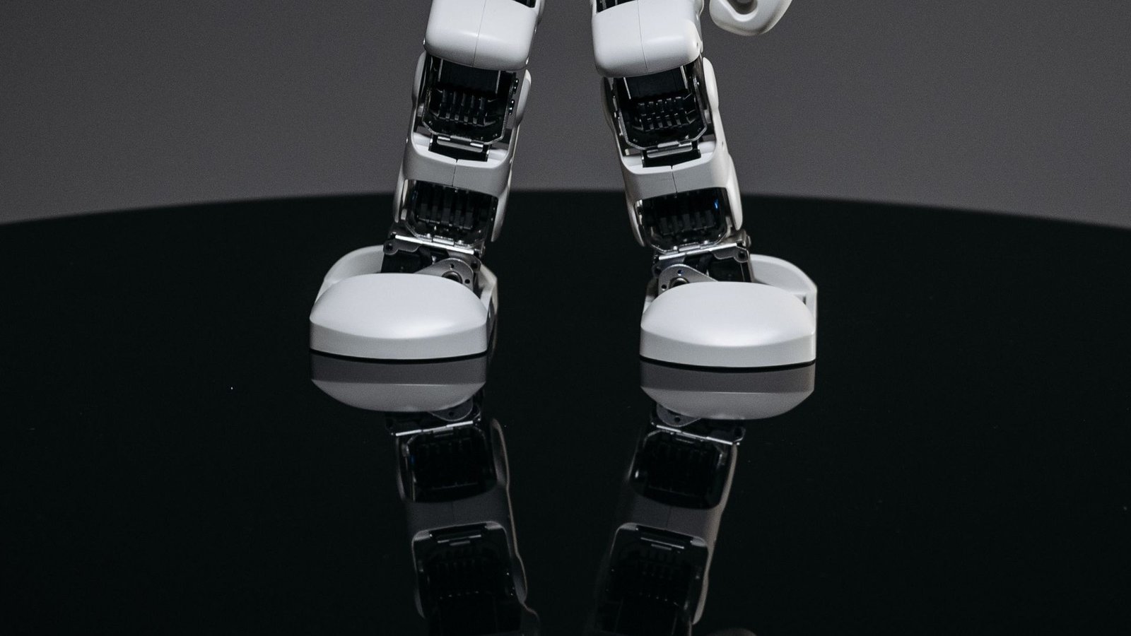 Close-up of a small white humanoid robot on a dark surface