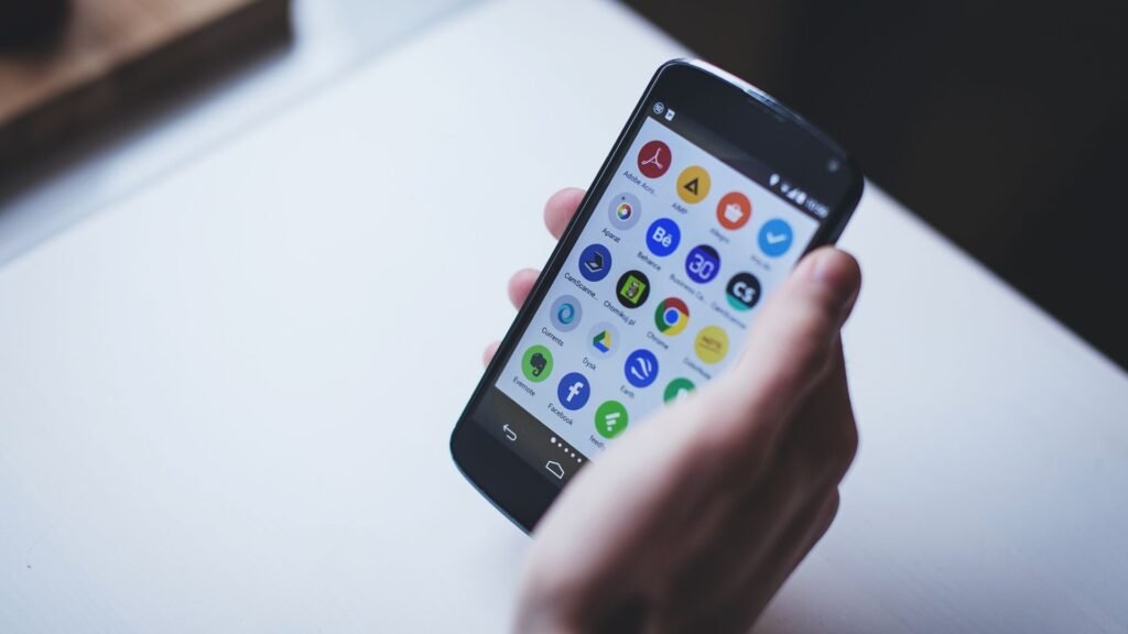 Hand holding an Android smartphone showing app icons on screen