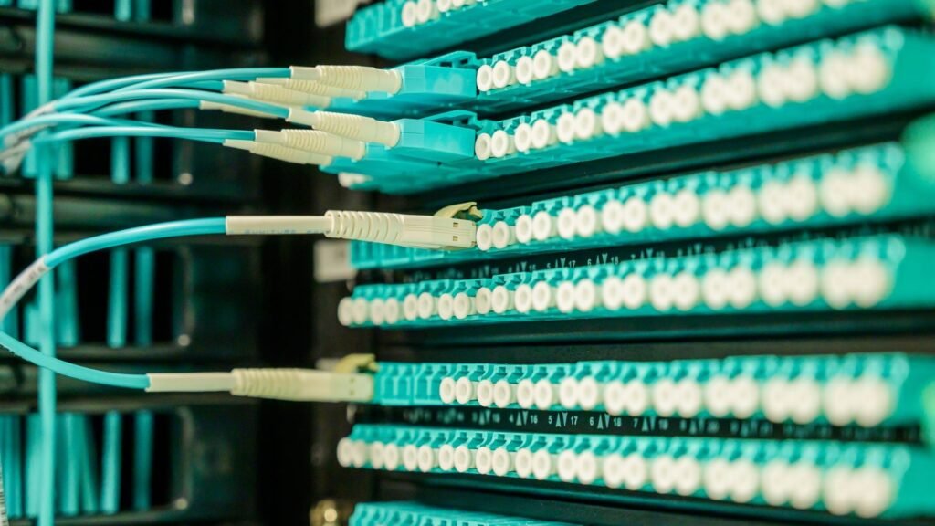 Close-up of teal fiber-optic connectors plugged into a network patch panel