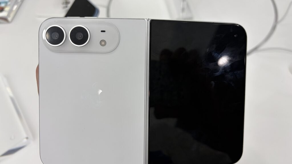 Unfolded white iPhone Duo held in a hand, showing the dual-camera plateau and Apple logo on the back