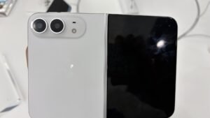Unfolded white iPhone Duo held in a hand, showing the dual-camera plateau and Apple logo on the back
