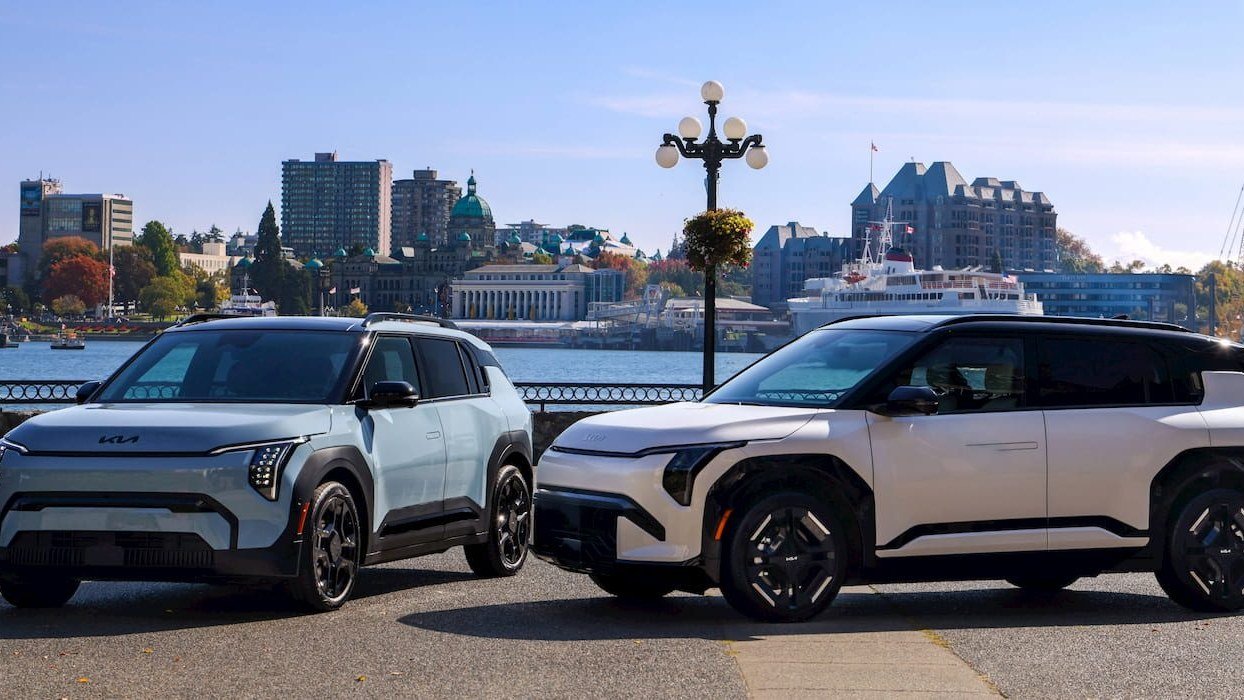 Two Kia EV3 electric SUVs parked by a waterfront under a bright blue sky