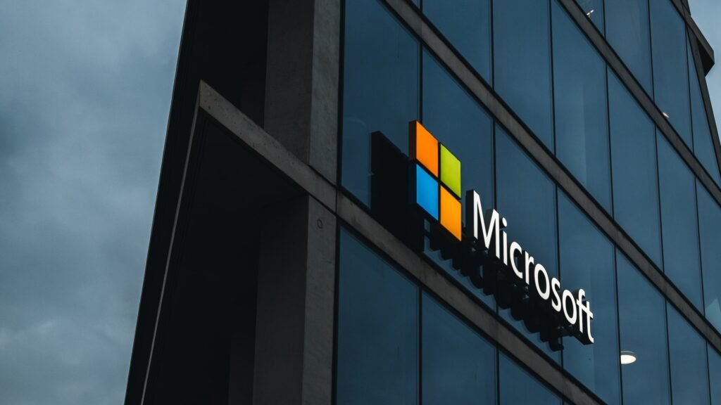 Glass Microsoft office tower with the illuminated logo against a moody evening sky