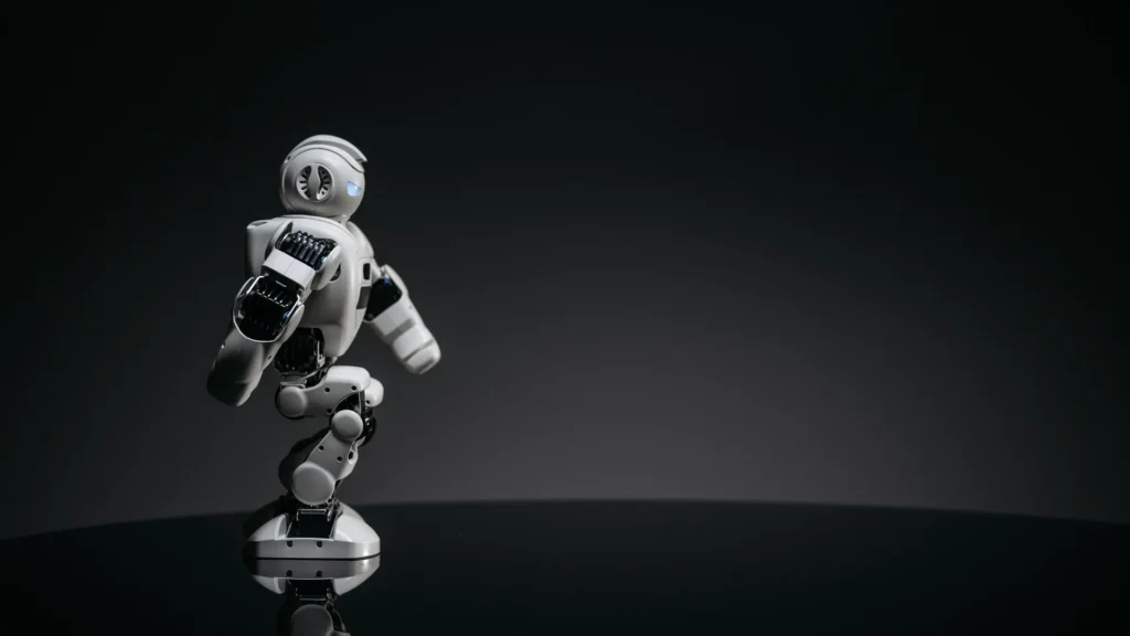 White humanoid robot walking across a dark studio floor