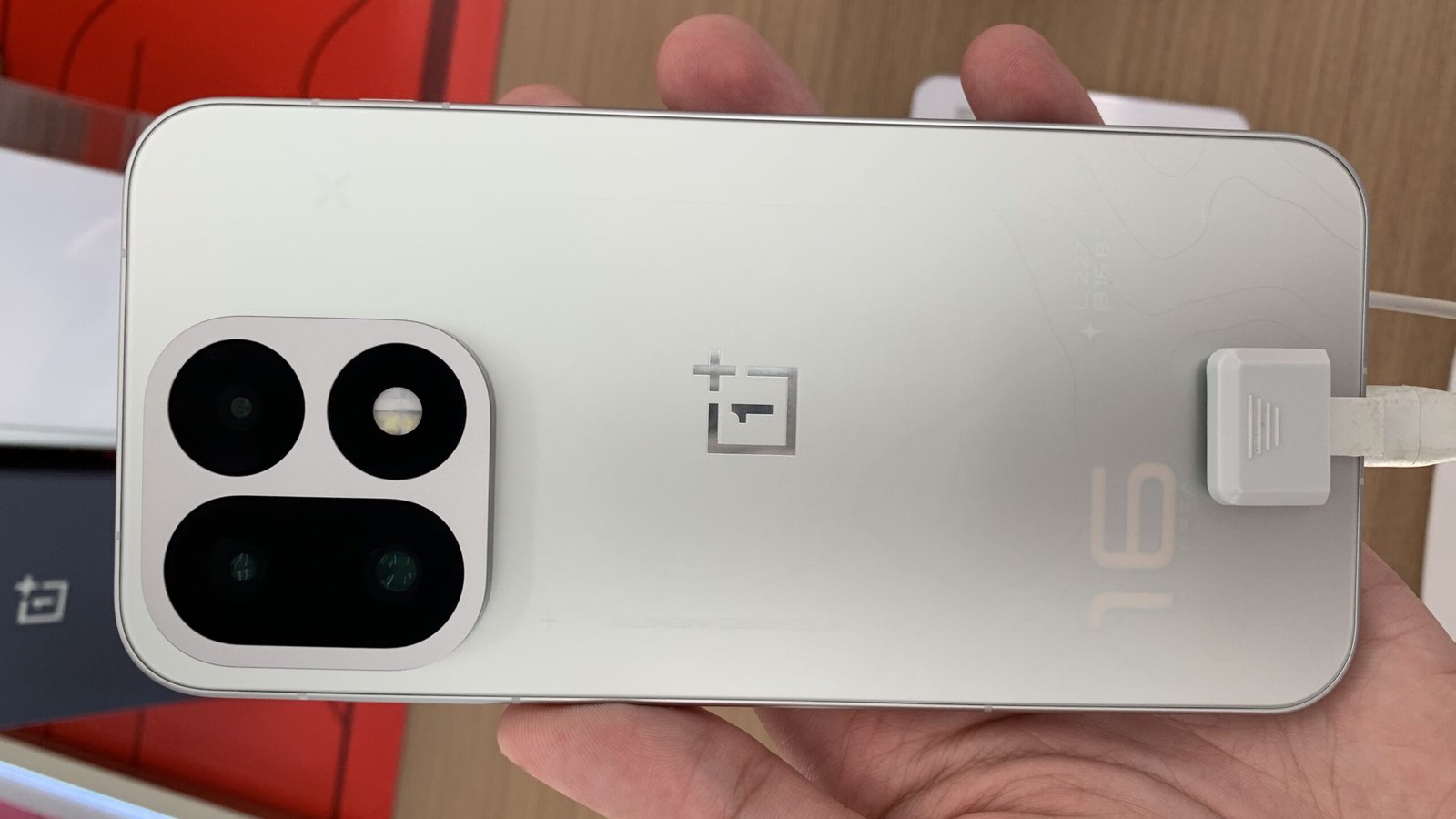 OnePlus 16 held in hand, showing its rear camera module