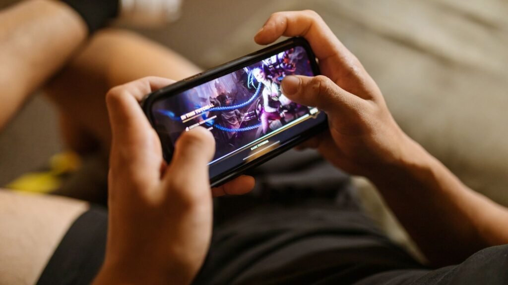 Hands holding a smartphone in landscape mode during an intense mobile game