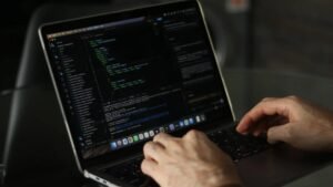 Close-up of a developer's hands typing code on a MacBook with a code editor on screen