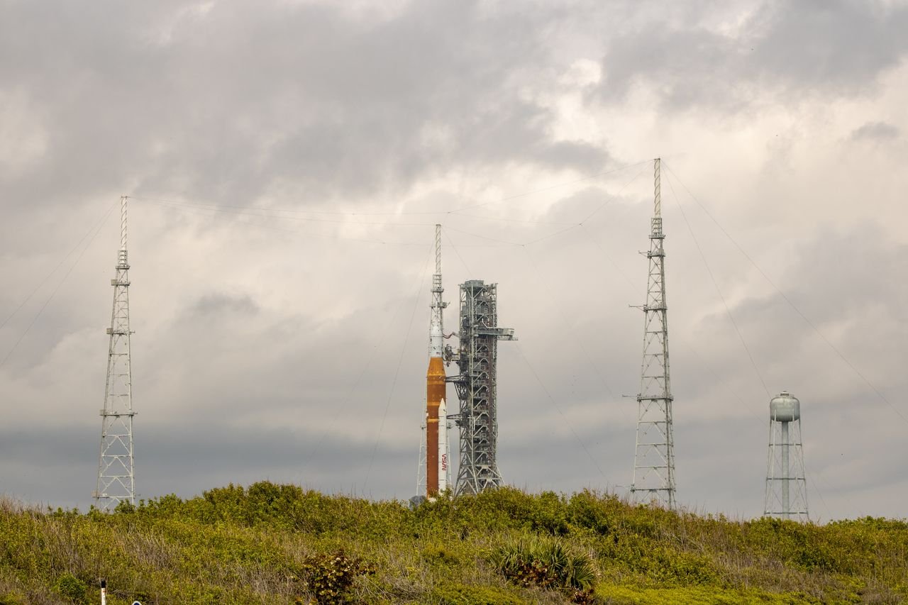 NASA SLS rocket on the launch pad at Kennedy Space Center under a dramatic sky