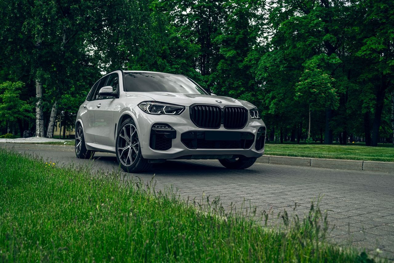 BMW iX5 electric SUV beside the outgoing X5 showing its slimmer grille and Double-X headlights
