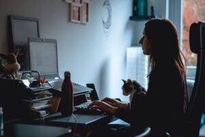 Person working at a laptop while a phone and calendar notifications sit nearby on a desk