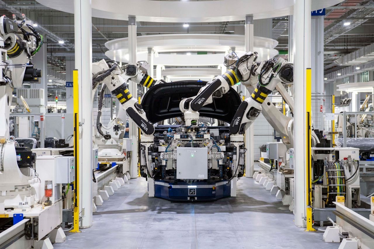 Robot arms assembling a car on an automotive production line in a modern factory