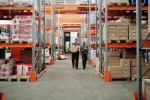 Humanoid robot moving storage totes along a warehouse conveyor line