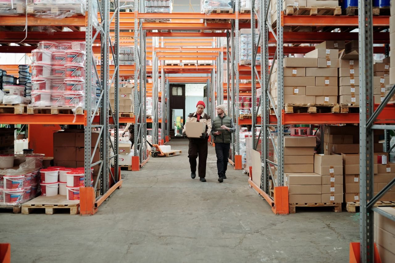 Humanoid robot moving storage totes along a warehouse conveyor line