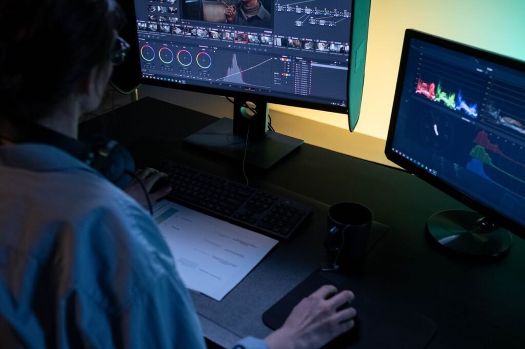 Video editor working on a colourful timeline across dual monitors in a dark editing studio
