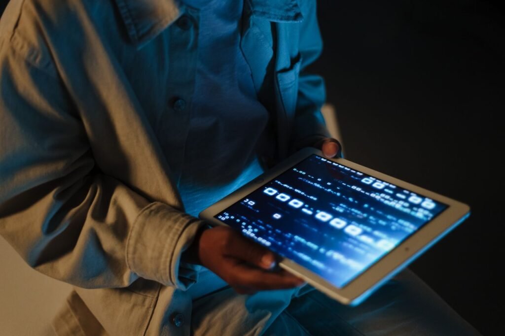 Hand holding a slim tablet with a bright OLED display showing vivid colors