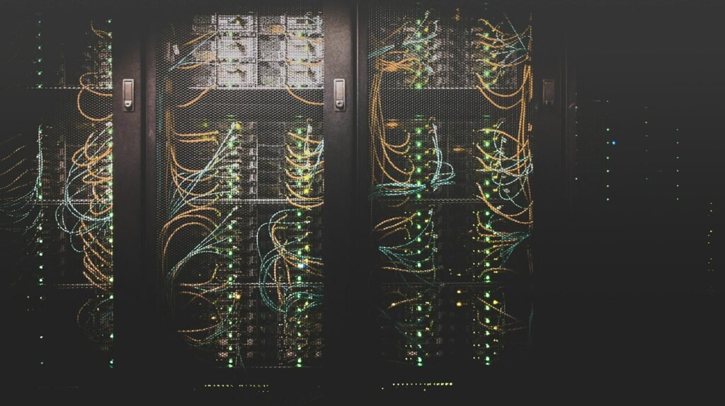 Server racks with glowing network cables and indicator lights in a dark data center
