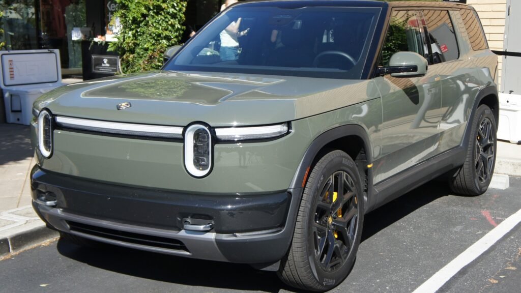 Olive-green Rivian R2 electric SUV parked at a Rivian facility