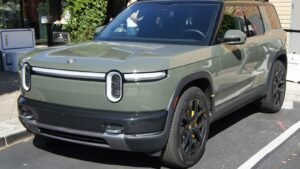 Olive-green Rivian R2 electric SUV parked at a Rivian facility