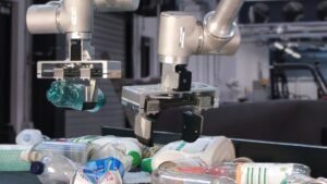 Danu Robotics' H.E.R.O. robot arm gripping a plastic bottle over a conveyor of recyclables