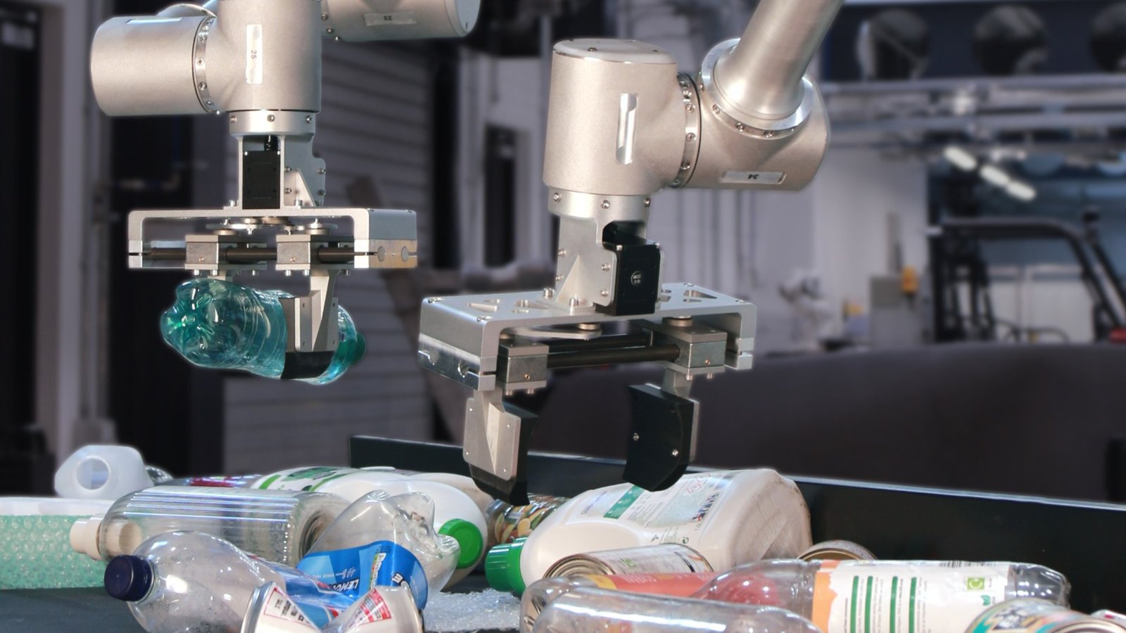 Danu Robotics' H.E.R.O. robot arm gripping a plastic bottle over a conveyor of recyclables