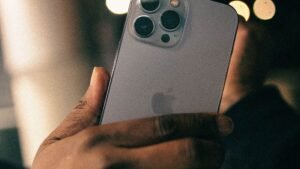 Hand holding an iPhone Pro with triple camera against night city lights