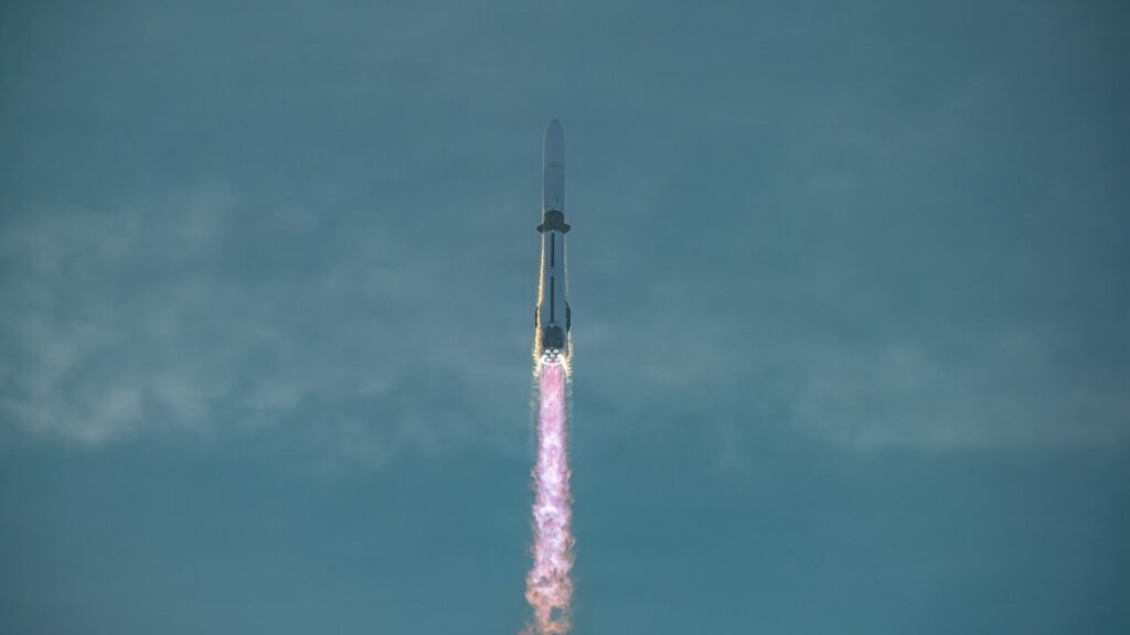 Blue Origin's New Glenn rocket ascending at dusk with its engines firing and a bright exhaust plume