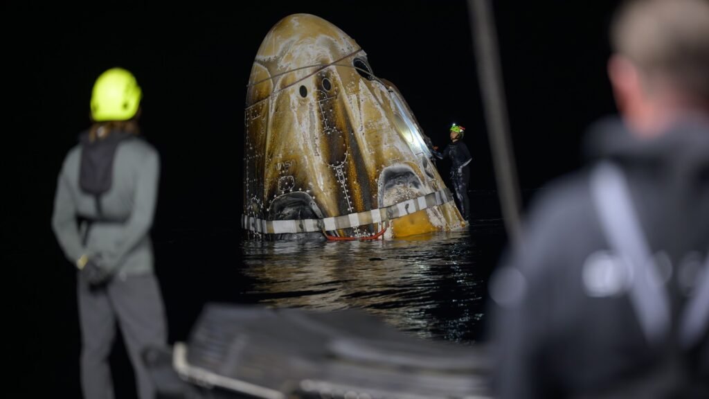 SpaceX Crew Dragon capsule floating in the Pacific Ocean after splashdown at night