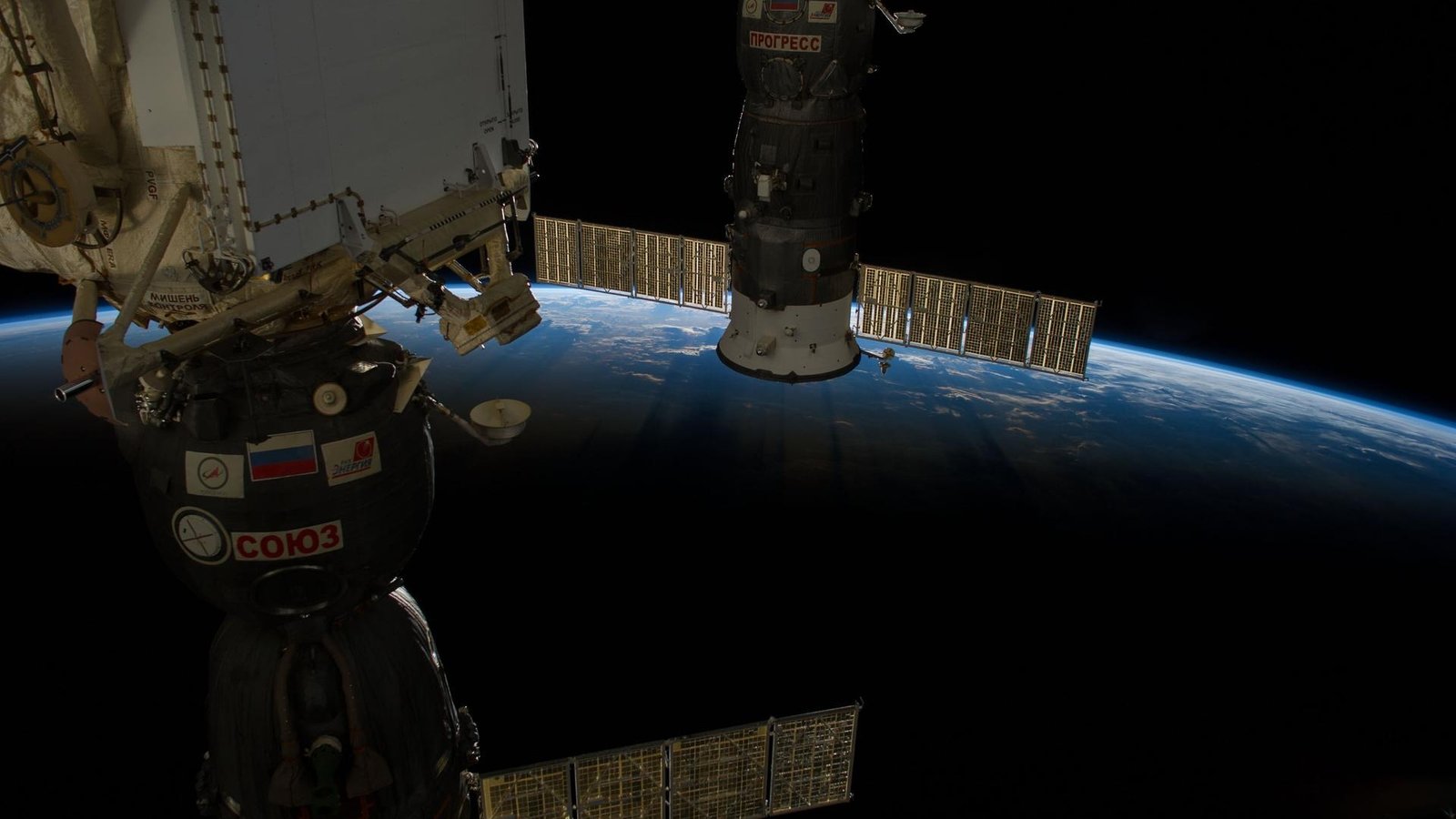 Docked Soyuz and Progress spacecraft at the International Space Station against Earth's glowing blue horizon