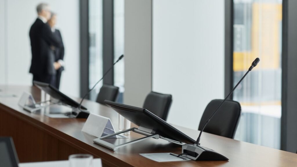 Conference table with gooseneck microphones and monitors in a modern meeting room