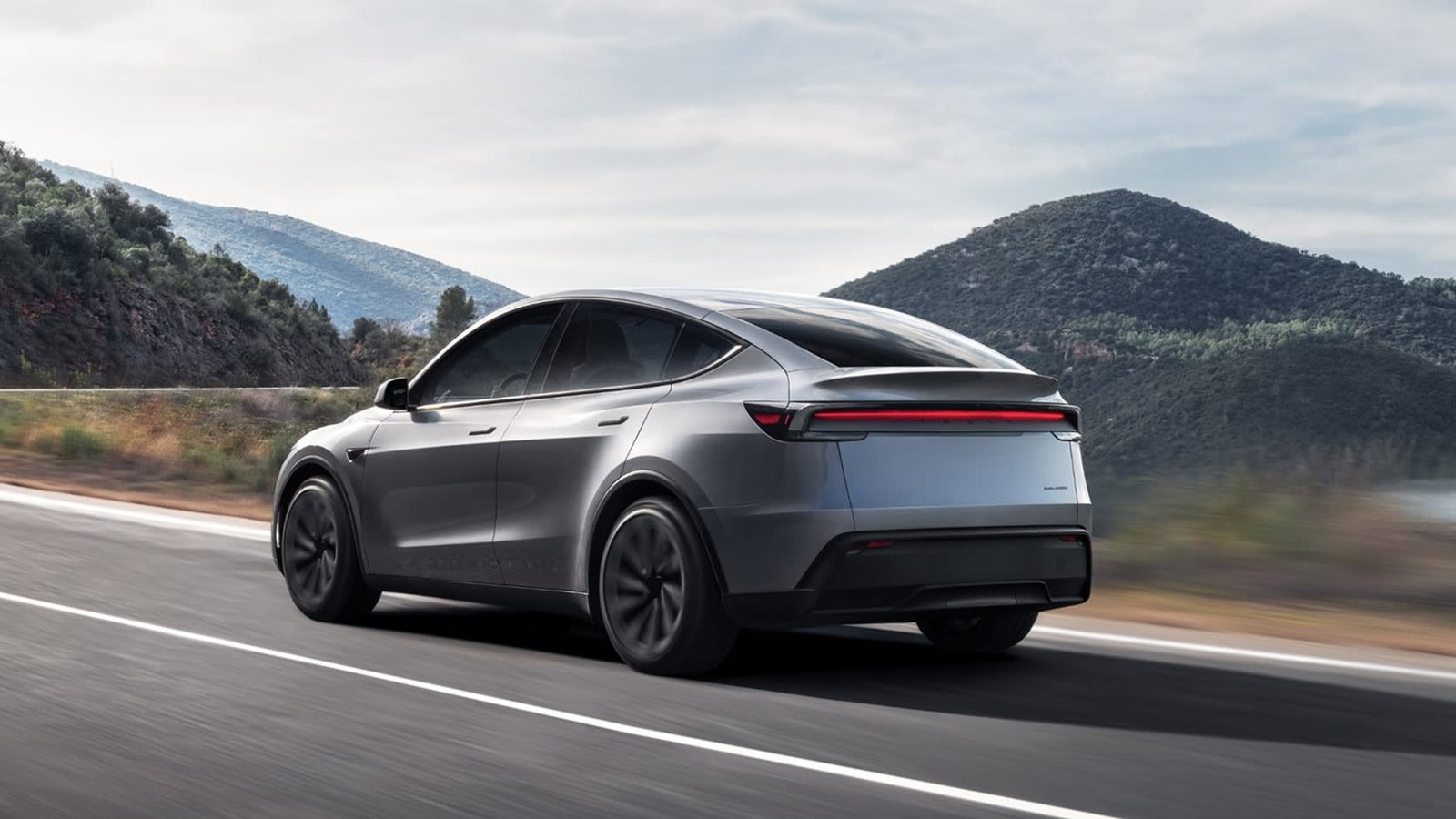 Silver Tesla Model Y driving on a winding mountain road