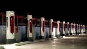 A row of Tesla Supercharger stalls glowing at night