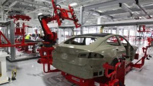 Red robotic arms working on a Tesla Model S body on the assembly line inside the Tesla factory in Fremont